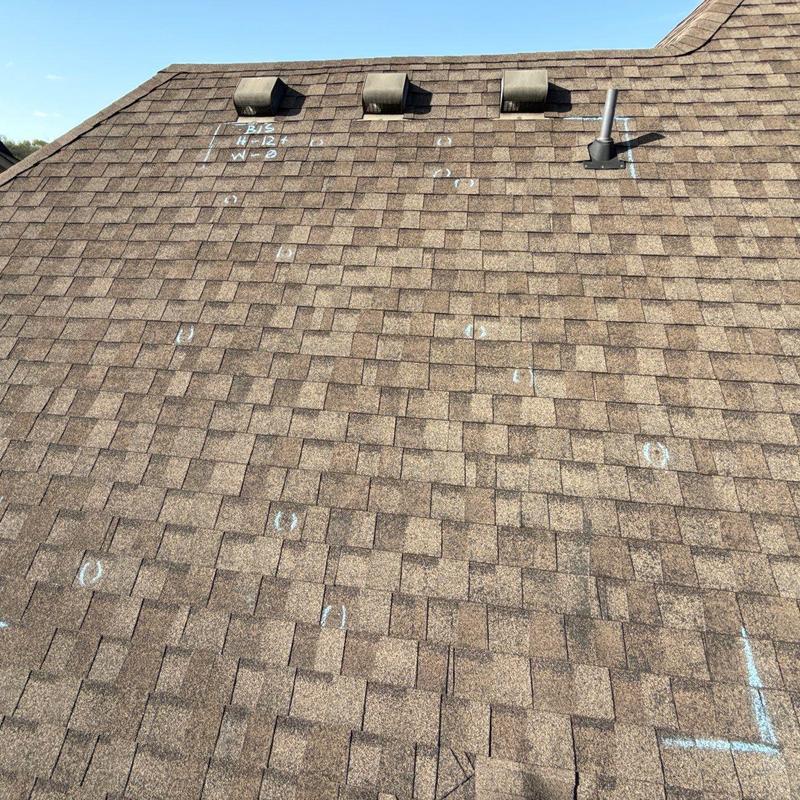 Asphalt shingles with hail damage marked for inspection