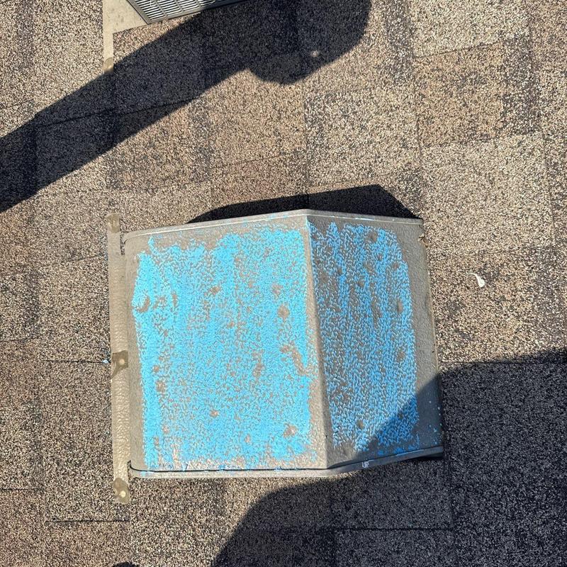 Roof vent with peeling blue paint on asphalt shingles