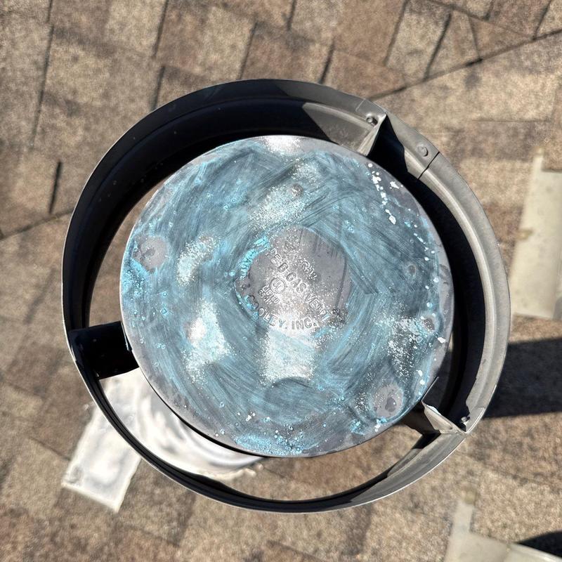 Metal roof vent cap with corrosion on asphalt shingles