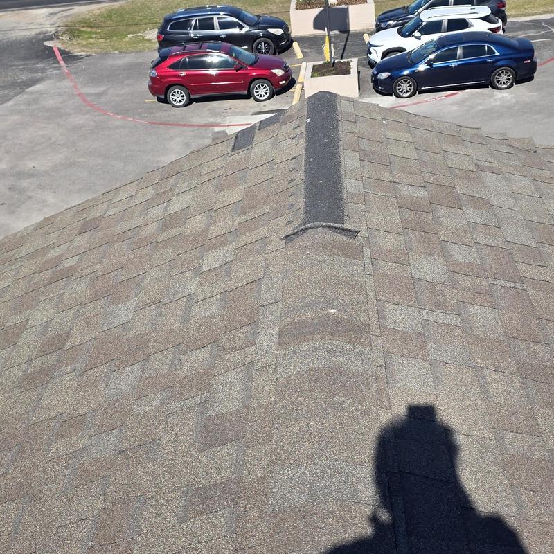 Asphalt shingle roof ridge with wind and hail damage