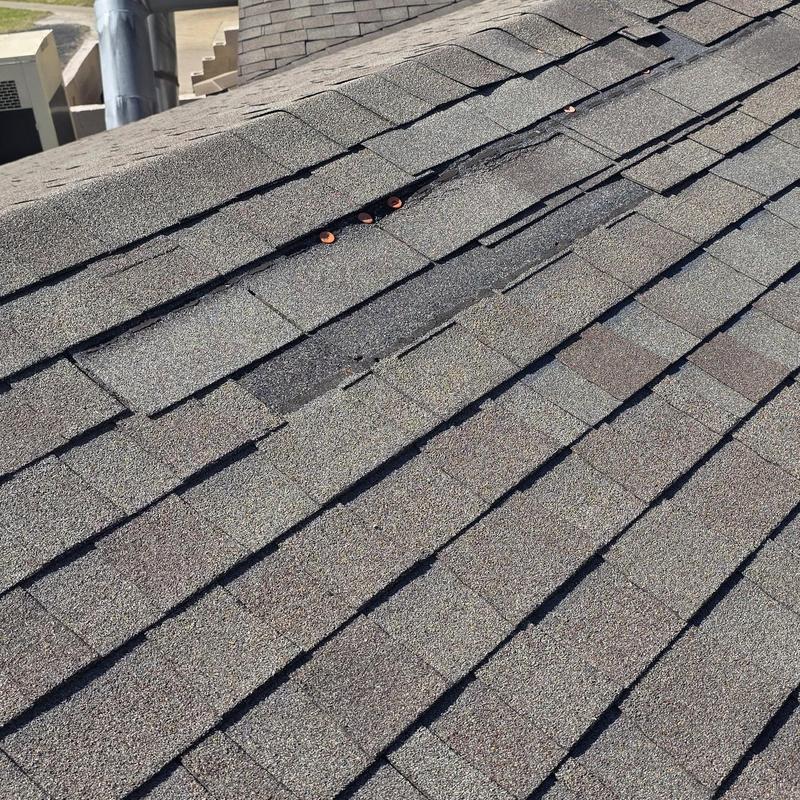 Roof shingles with hail and wind damage near ridge vent