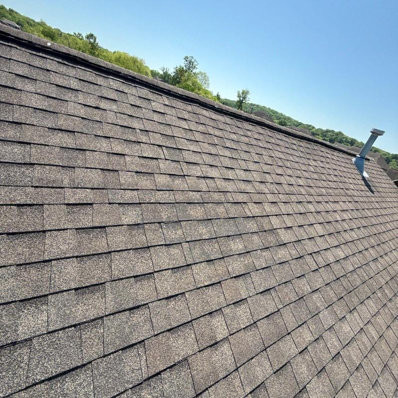 Asphalt shingle roof with ventilation pipe on sunny day