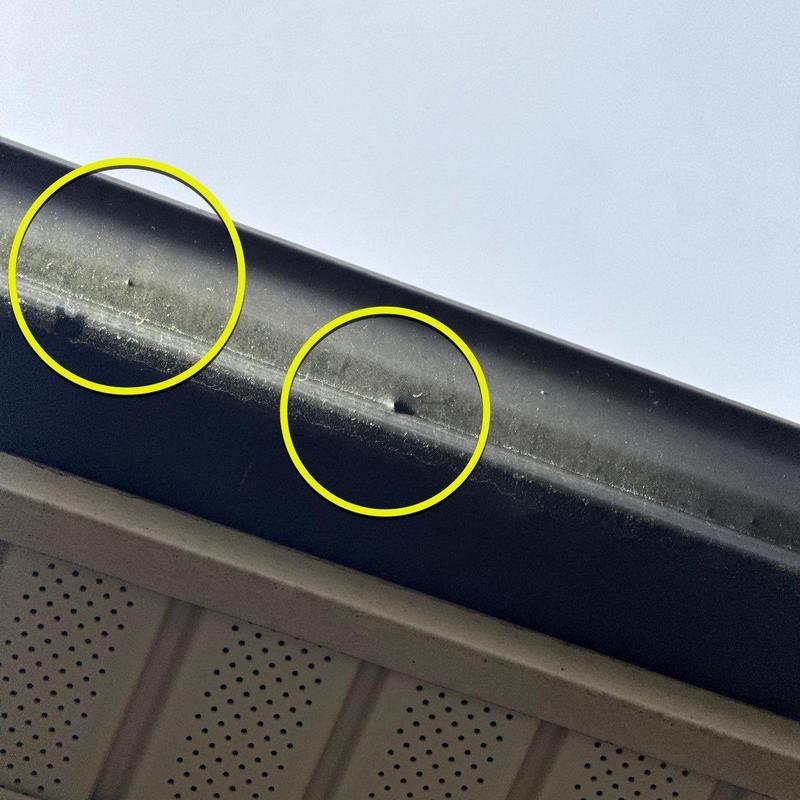 Gutter with hail damage dents marked by yellow circles