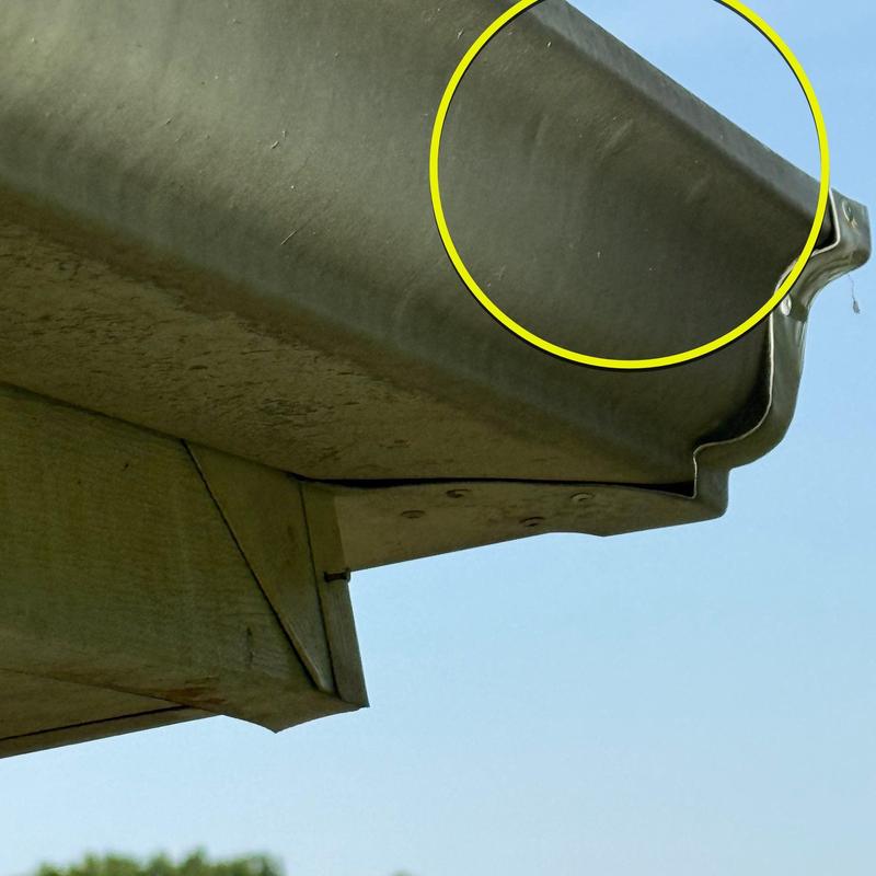 Metal gutter dent with circled area showing damage
