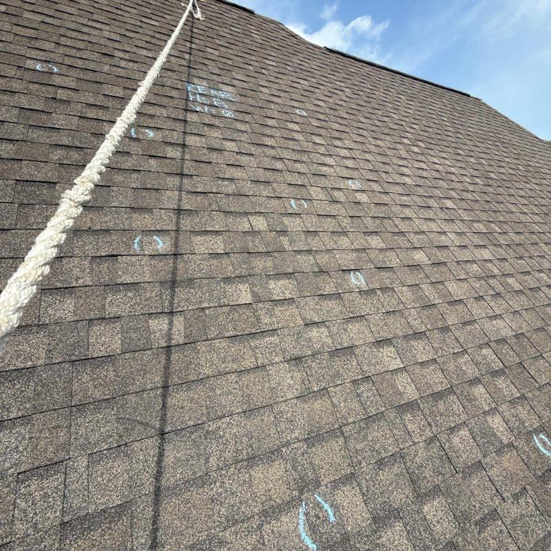Asphalt shingle roof with hail damage markings and rope