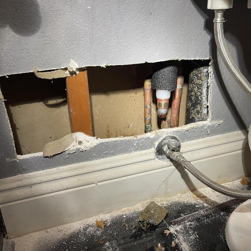 Copper water line behind bathroom wall with access hole