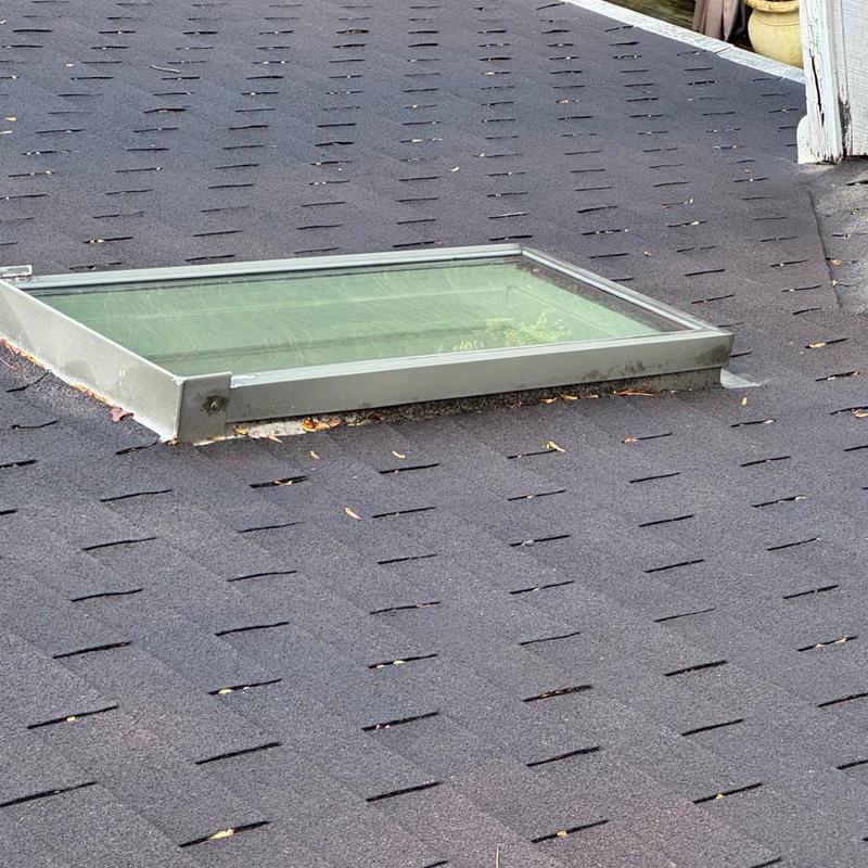 Skylight and asphalt shingle roof with debris and wear