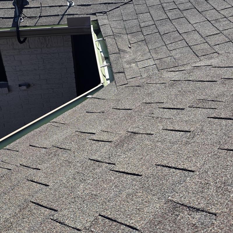 Asphalt shingle roof with hail damage near chimney