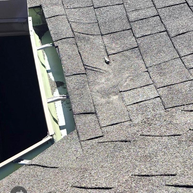 Asphalt roof shingles with hail damage near vent pipe