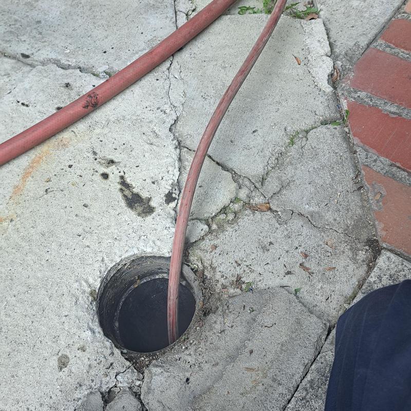 Sewer cleanout with jetter hose on cracked concrete