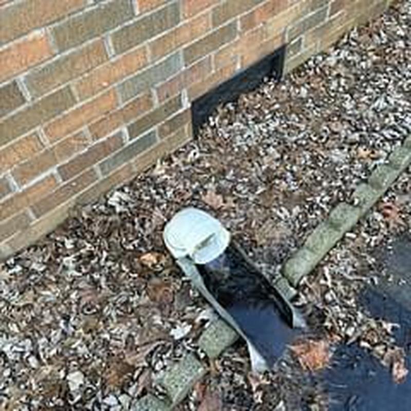 Main sewer cleanout pipe exposed near brick house wall