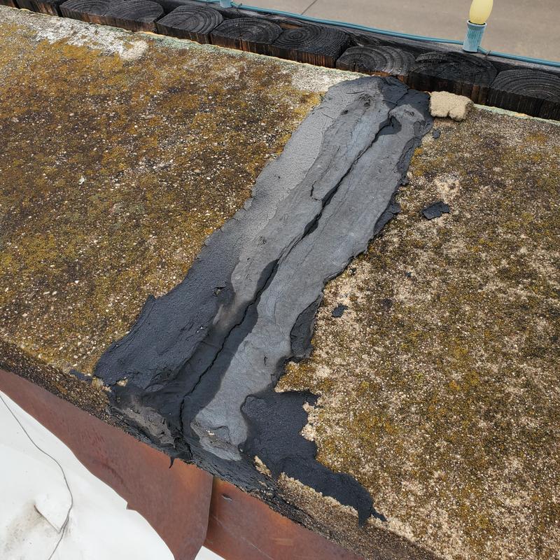 Flat roof sealant patch showing hail and wind damage
