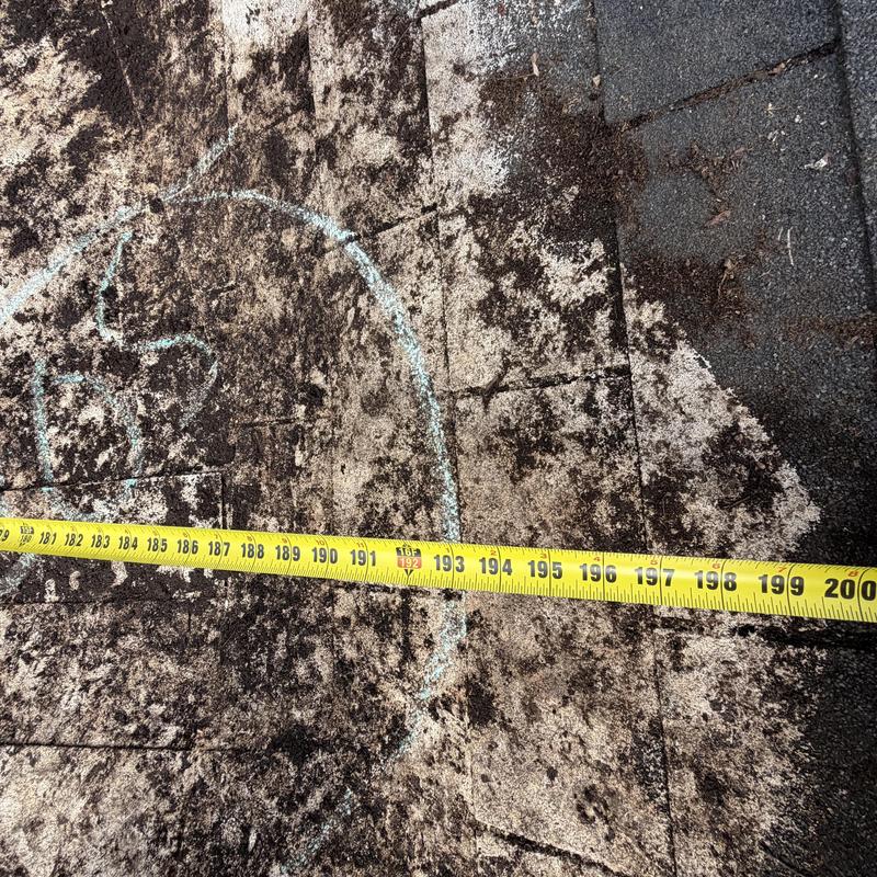 3-tab shingle roof with leak damage marked by tape measure