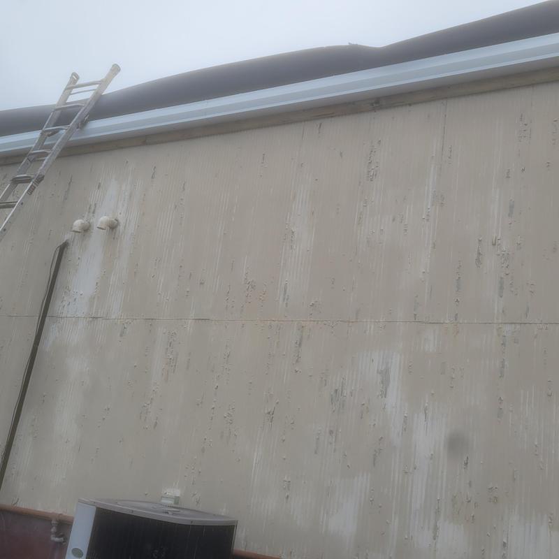 Commercial roof gutter and downspout installation with ladder