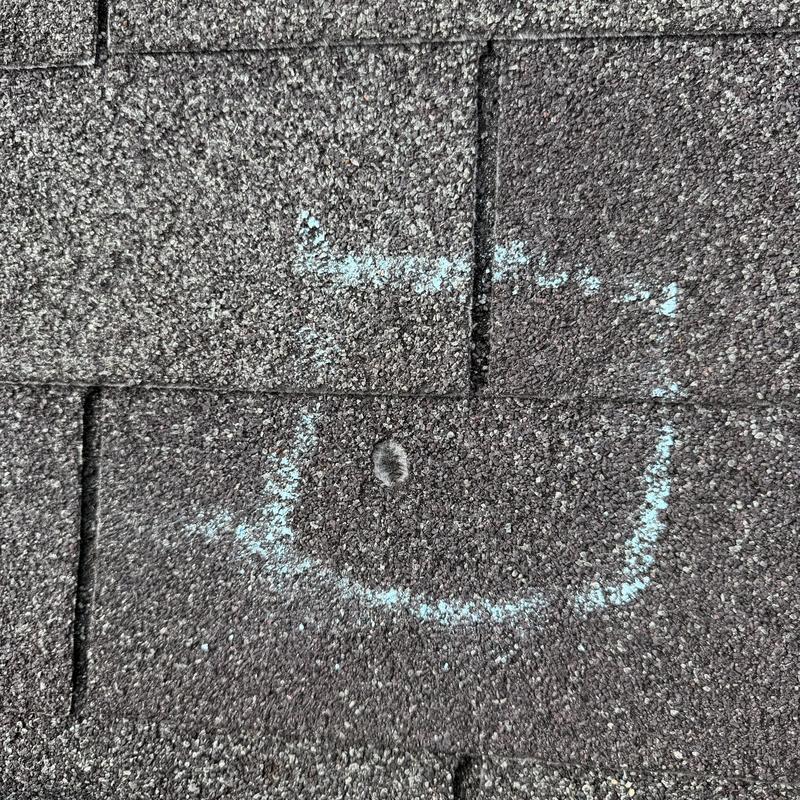 Three-tab shingle roof with marked hail damage spot