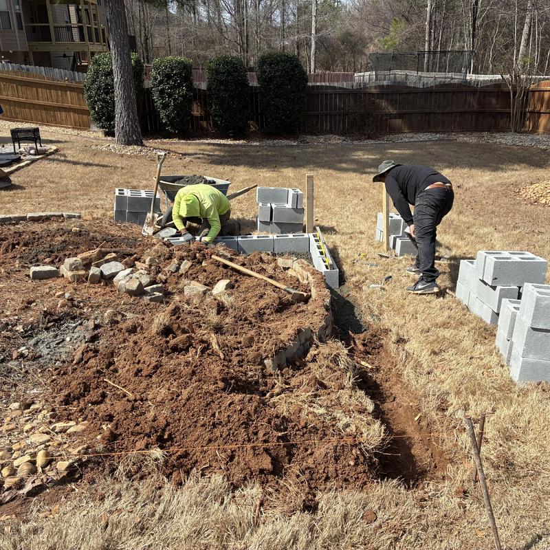 Retaining wall foundation with concrete block laying