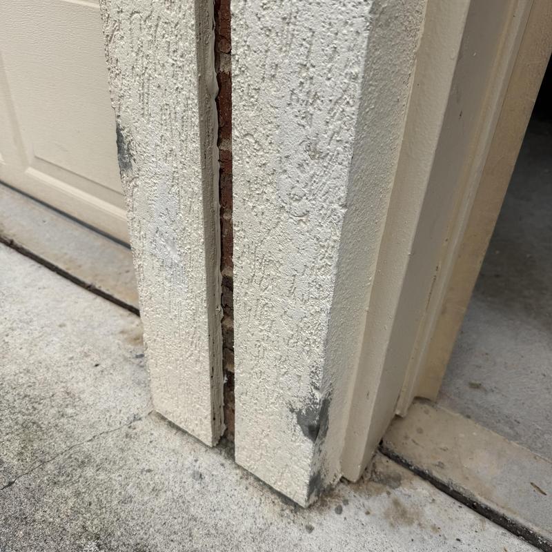Stucco wall damage and gaps near garage door frame