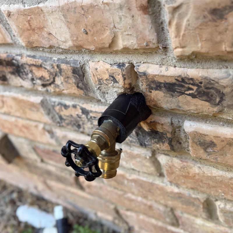 Outdoor hose bib with shutoff valve on brick wall