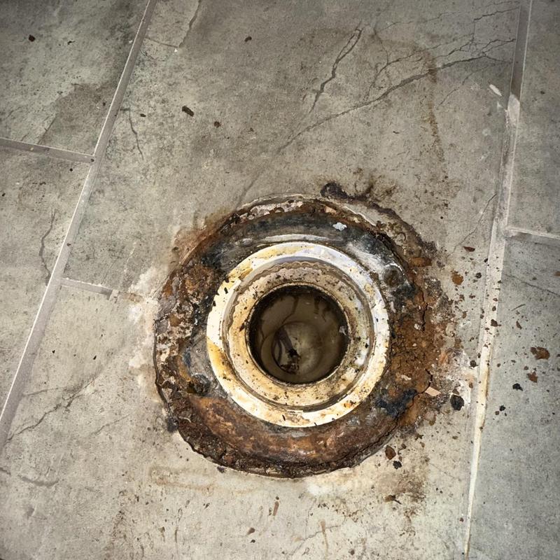 Toilet flange rust damage on tiled floor