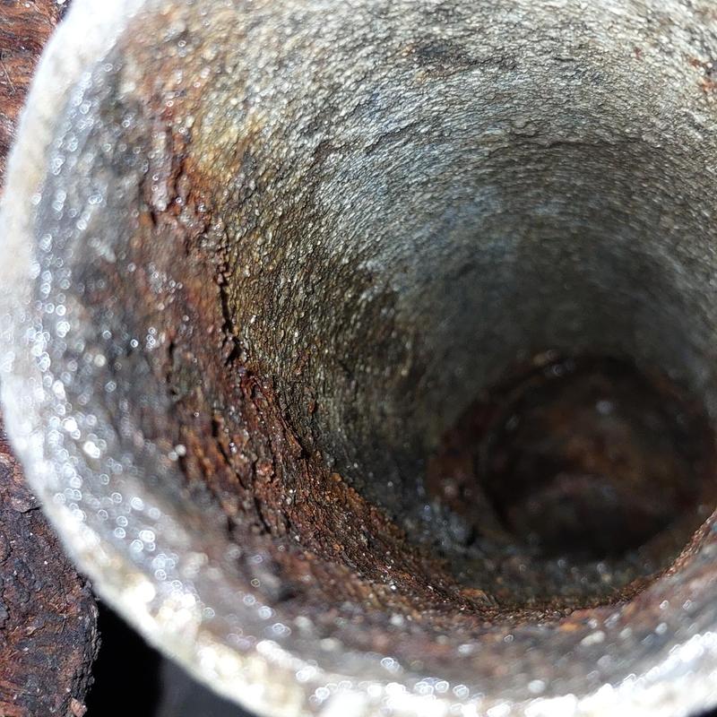 Corroded drain pipe interior with rust buildup
