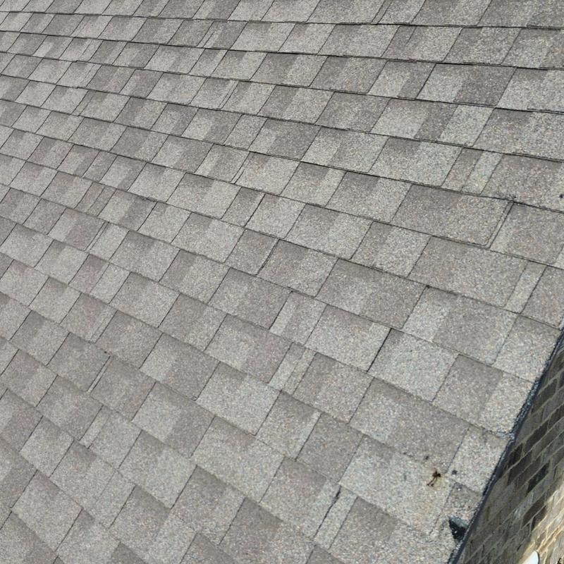 Asphalt roof shingles with minor damage near edge