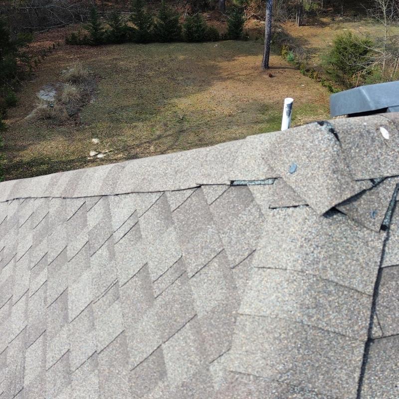 Roof shingles with damaged ridge cap at roof peak
