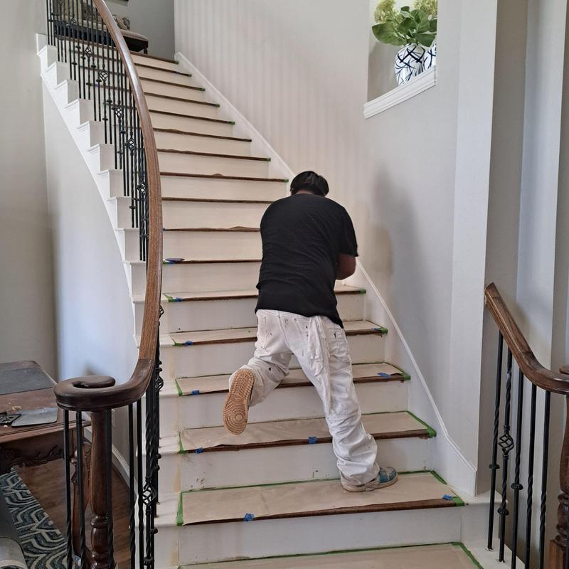 Hardwood stair treads being stained on curved staircase
