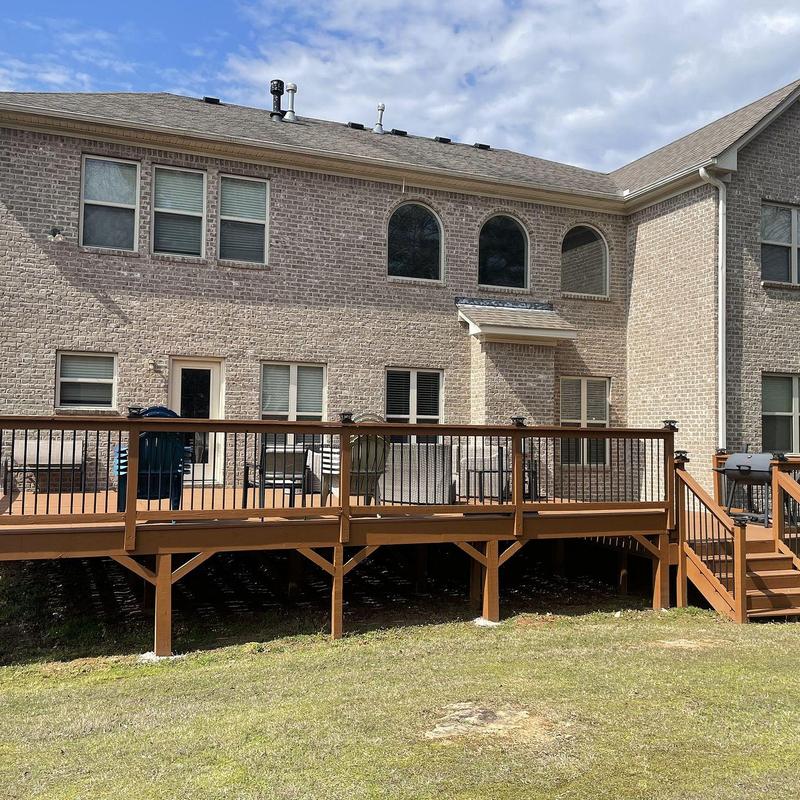 Wooden deck with railing and stairs on brick house