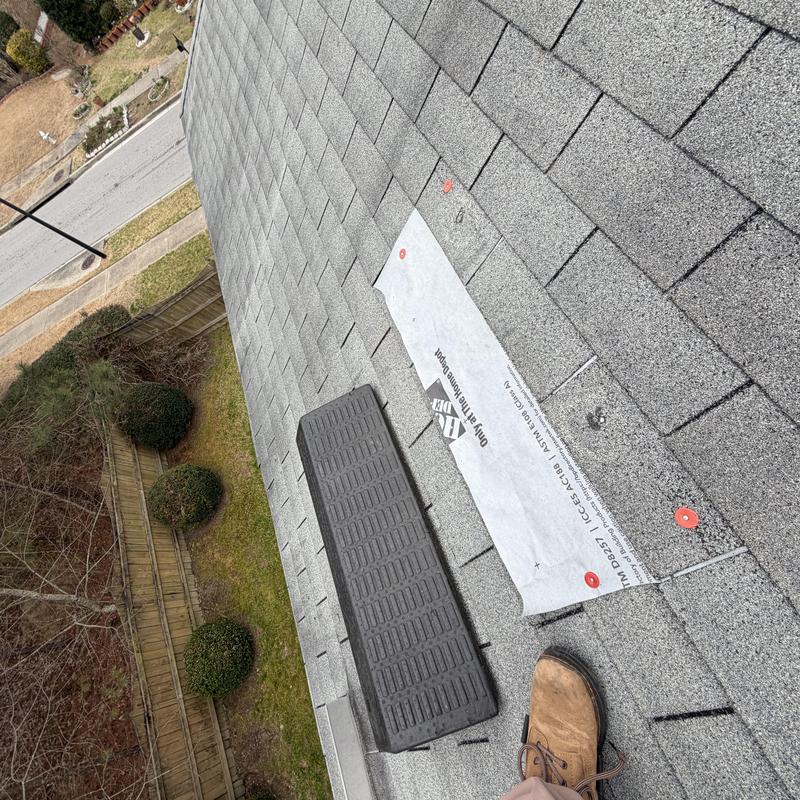 Roof shingles with tarped repair and pipe boot nearby