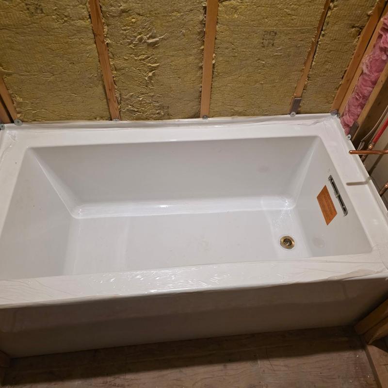 Soaker tub installed with drain and plumbing lines