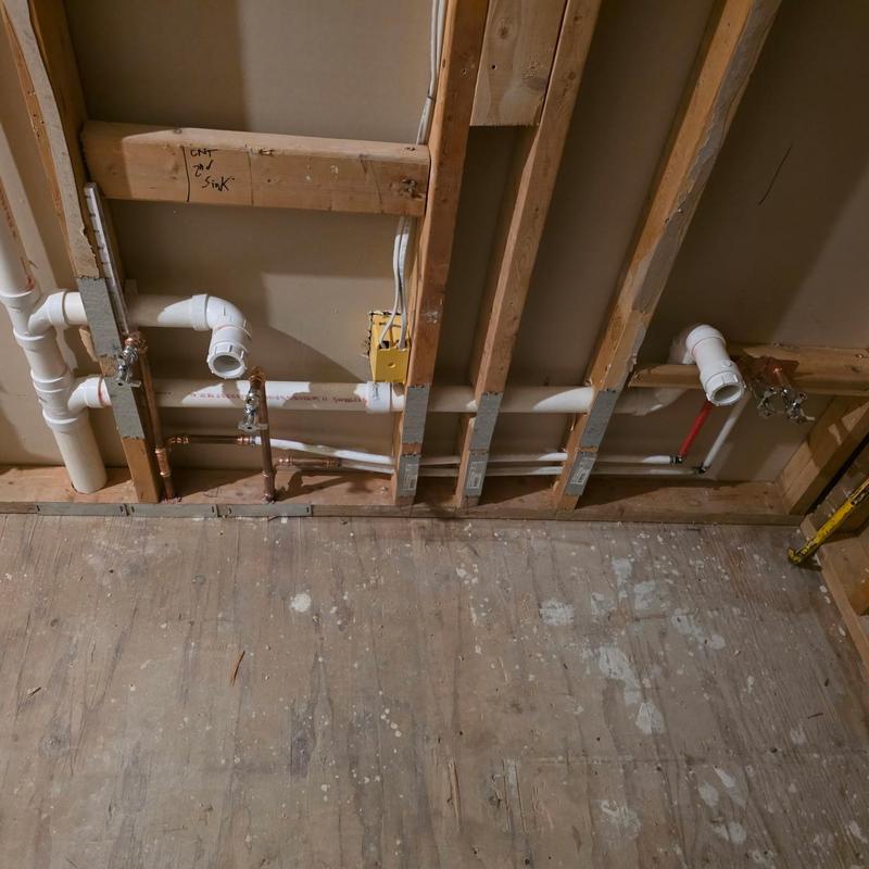 PVC drain and water lines installed in wall framing