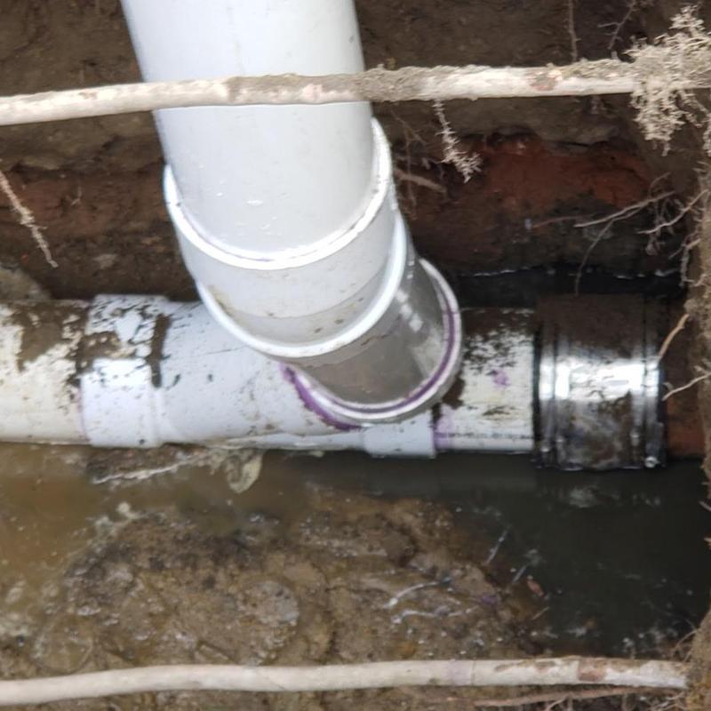 PVC sewer pipe with cleanout installation in muddy trench