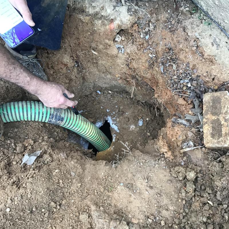 Septic tank with green pump hose in excavation site