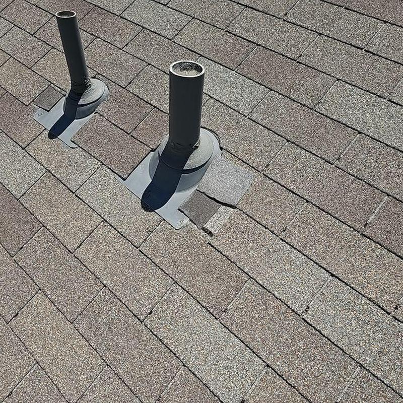 Shingle roof with minor wind damage near vent pipes Shingle roof with minor wind damage near vent pipes