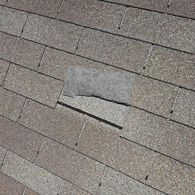 Asphalt shingle with minor wind damage on roof Asphalt shingle with minor wind damage on roof