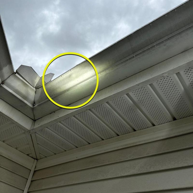 Metal gutter section with dent damage highlighted