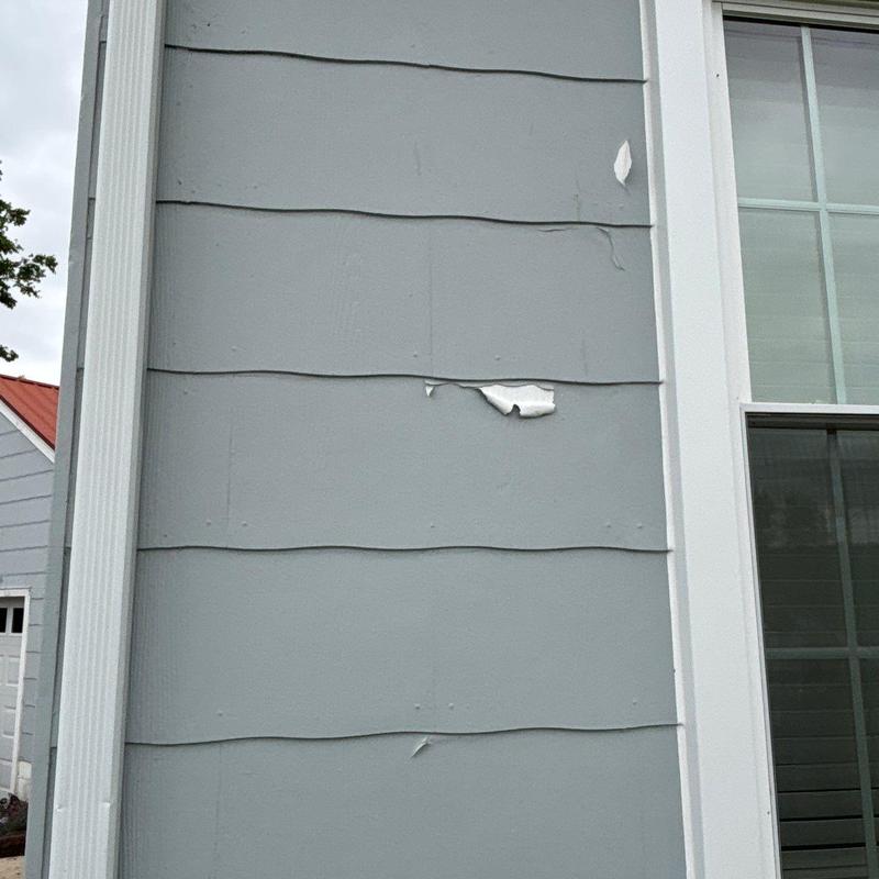 Exterior siding with peeling paint near window trim