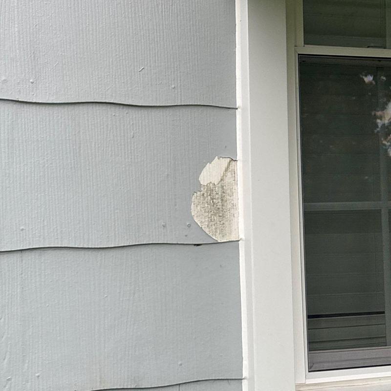 Exterior siding with peeling paint near window frame