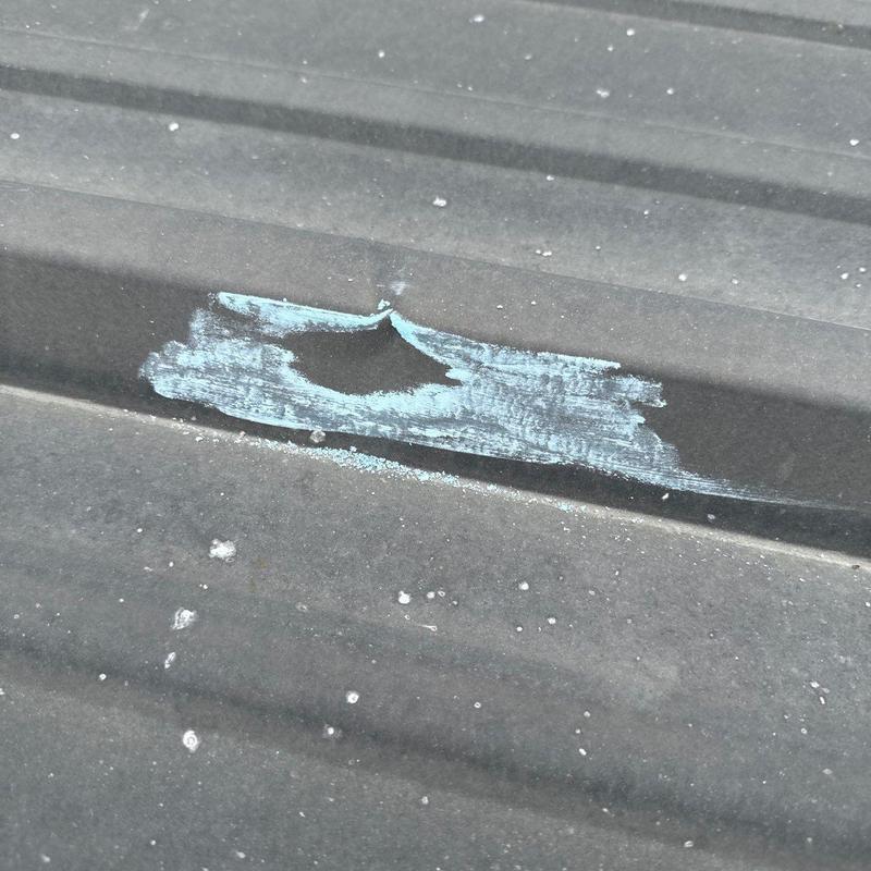 Metal roof panel with hail damage and paint abrasion
