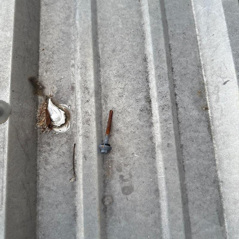 Metal roofing panel with removed rusted screw and sealant patch