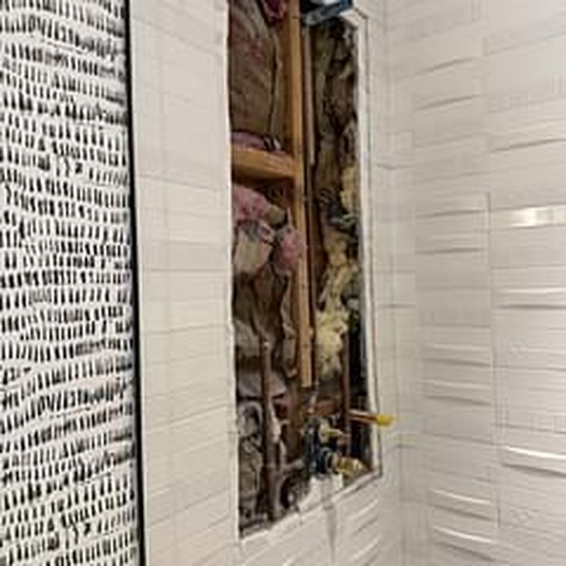 Shower plumbing rough-in with exposed insulation and studs