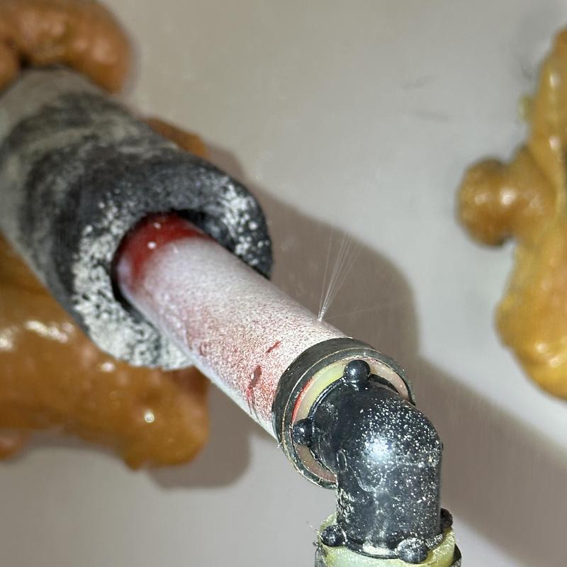 Uponor PEX pipe with pinhole leak spraying water