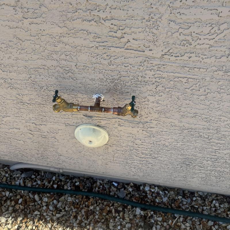 Hose bib with dual faucets on stucco wall