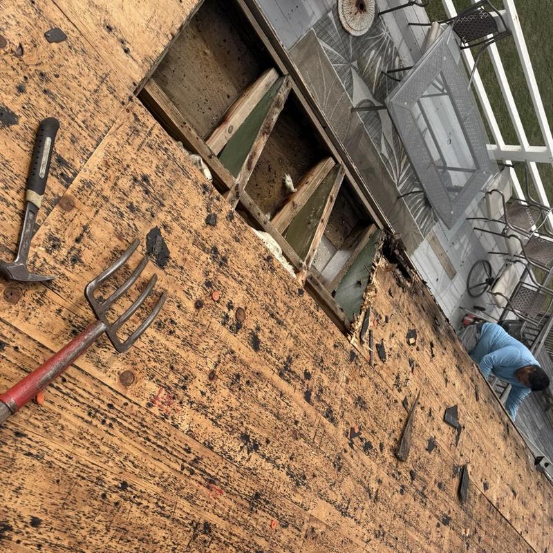 Roof decking removal exposing damaged wood and tools
