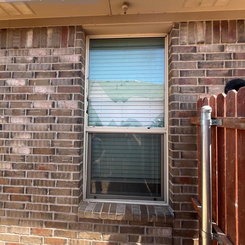 Double-pane window with storm damage repair in brick wall