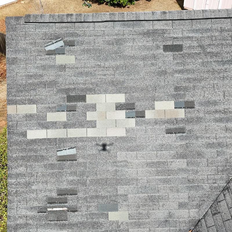 Roof shingles with multiple patch replacements on gray roof