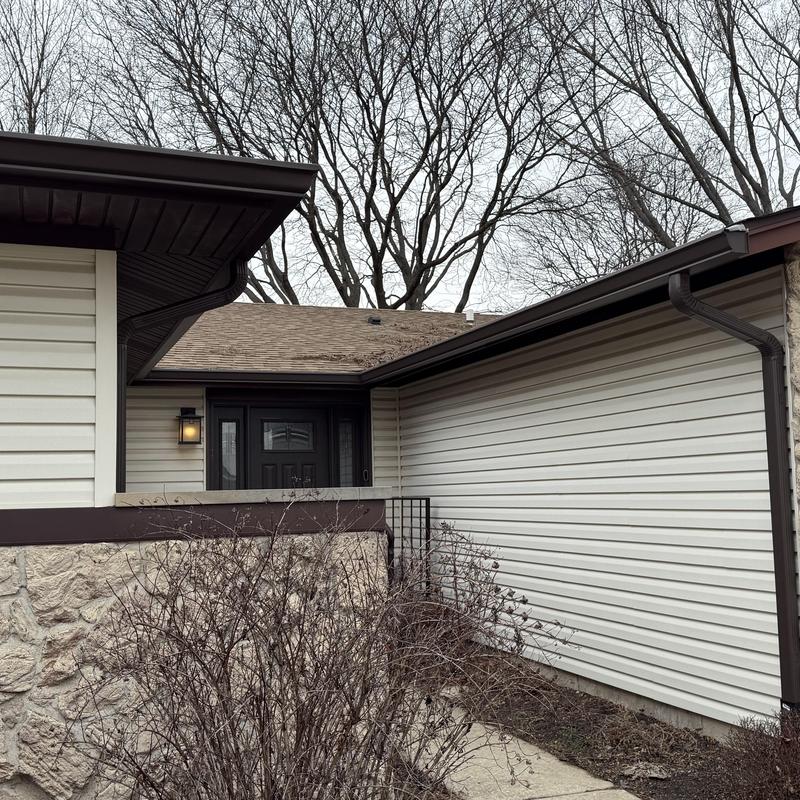 Gutter system with guards on beige house exterior