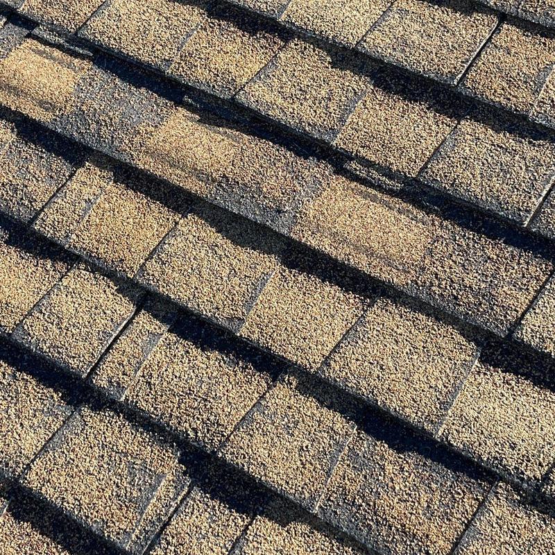 Asphalt shingles showing hail damage on roof surface