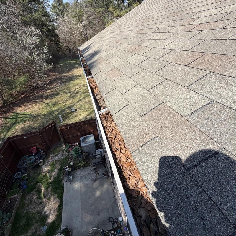 Gutter filled with dry leaves along asphalt roof edge