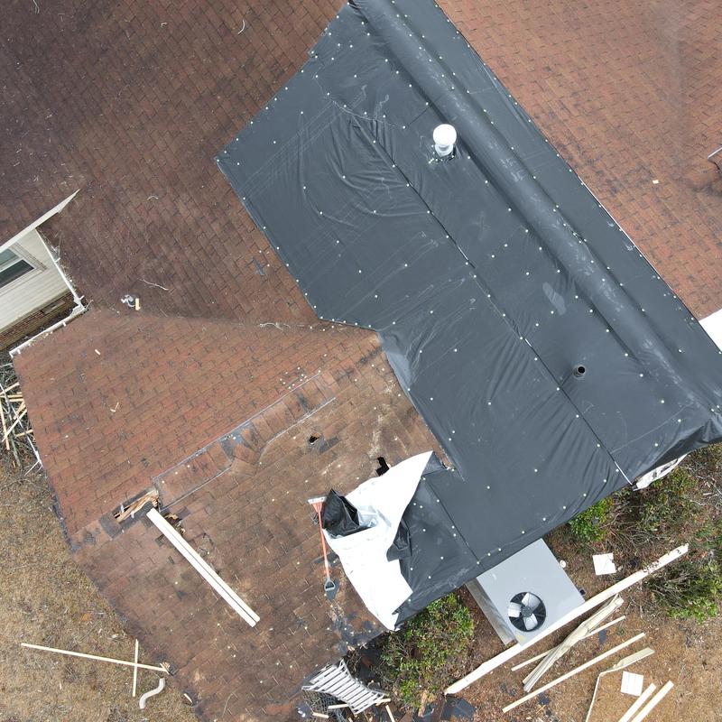 Shingle roof with tarp covering wind damage hole Shingle roof with tarp covering wind damage hole